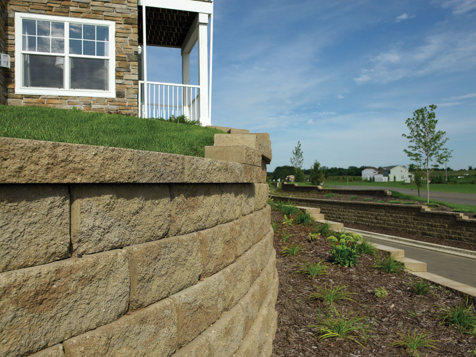 Close view of a curved and terraced Diamond Pro stone cut retaining wall with a planting area