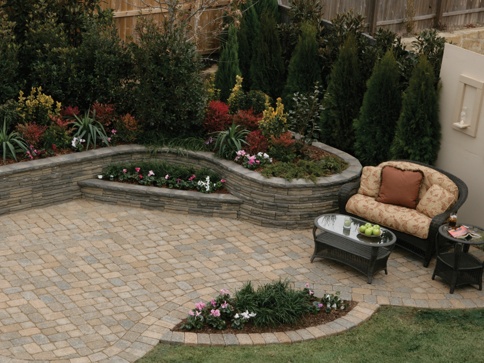 Overhead view of a paver patio with curved raised Natural Impressions Flagstone concrete block retaining wall planters and outdoor seating area. 
